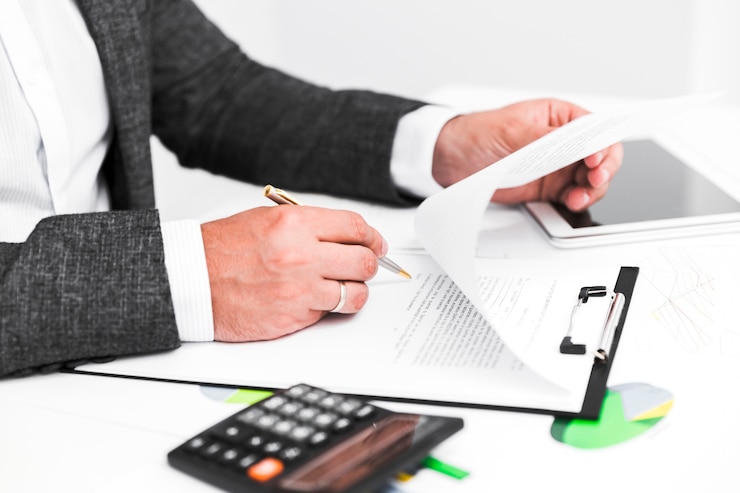 a businessman reviewing a document with a pen in hand, a calculator nearby