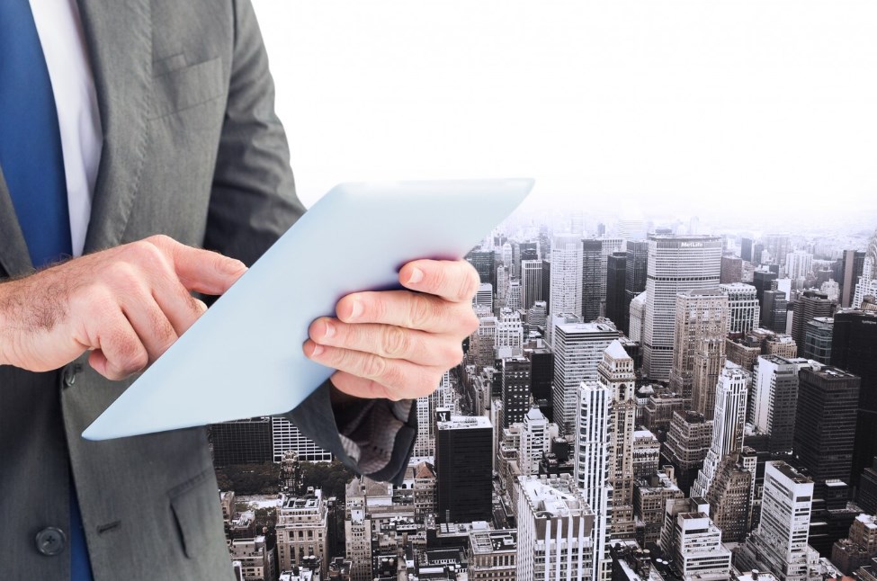 a businessman holding a tablet with city buildings in the background