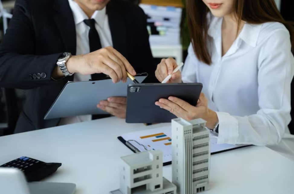 a businessman and a businesswoman working in real estate and using tablets